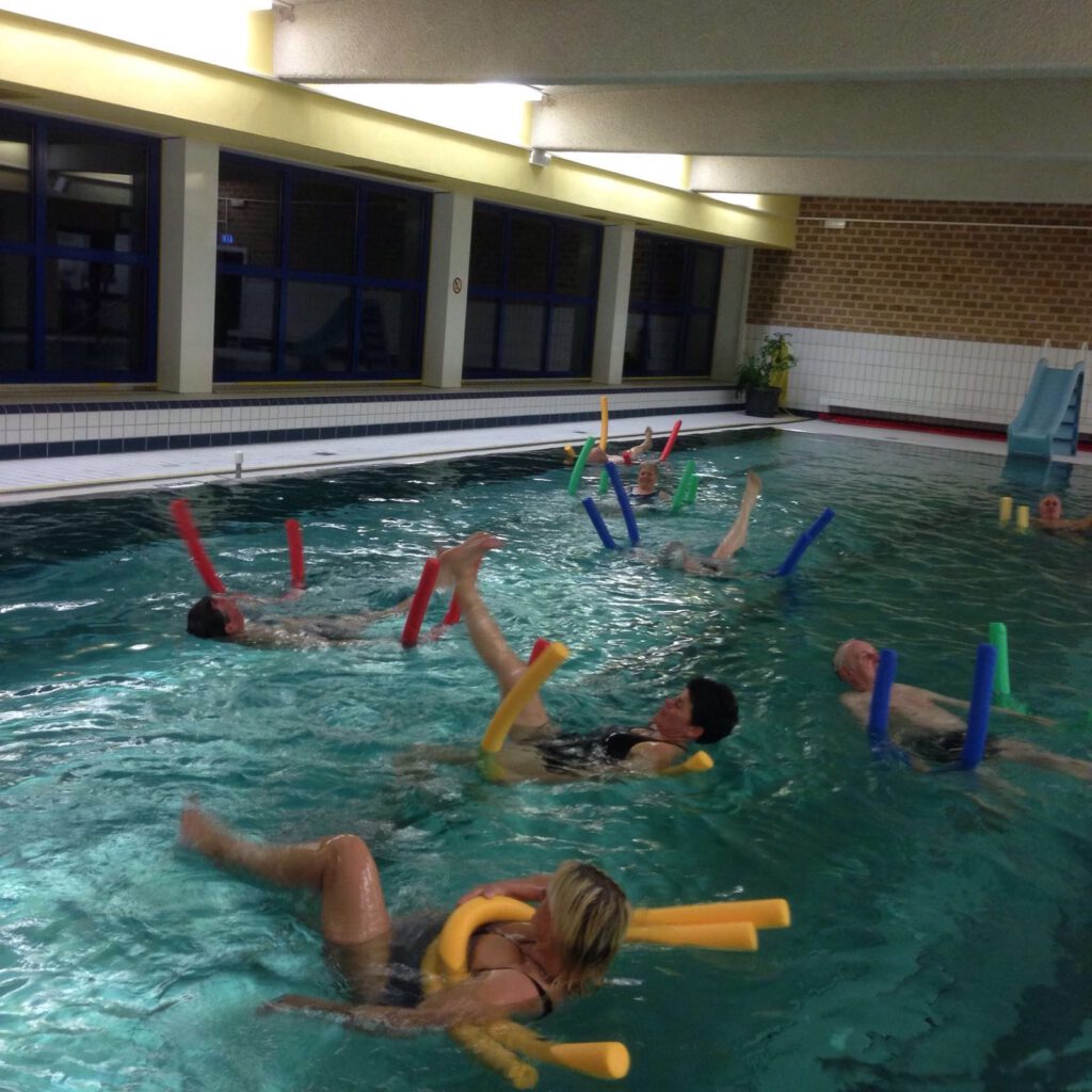 Wassergymnastik mit Schwimmnudeln in der Schwimmhalle